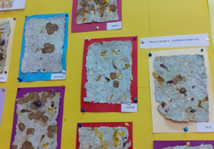 Zdjęcie przedstawia papier czerpany wykonany przez dzieci - wywieszony na tablicy w szatni przedszkolnej.